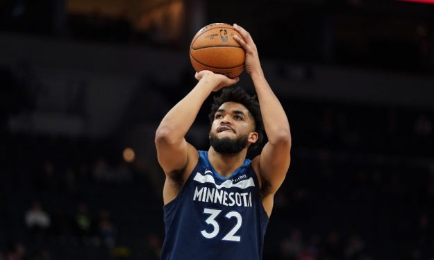 Karl-Anthony Towns in a Minnesota Timberwolves jersey, making a slam dunk during an NBA game.”